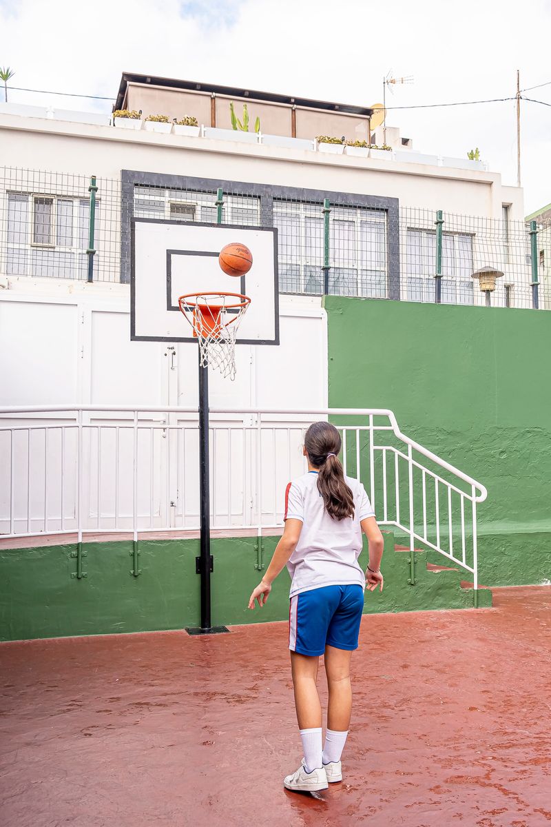 Una colegiala juega
          al baloncesto en el patio de recreo